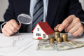 Professional property valuation survey — expert assessing house value with magnifying glass